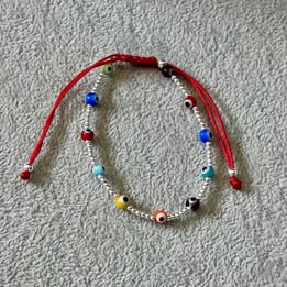 PULSERA AJUSTABLE HILO ROJO BOLITAS LISAS CON OJITO MULTICOLOR, PLATA .925